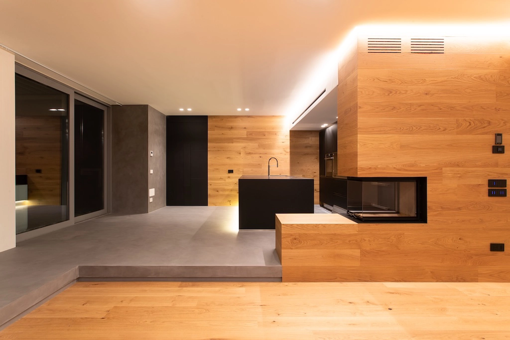 Casa BN — open plan space with black kitchen, wood cladding and integrated fireplace, interior design Vicenza