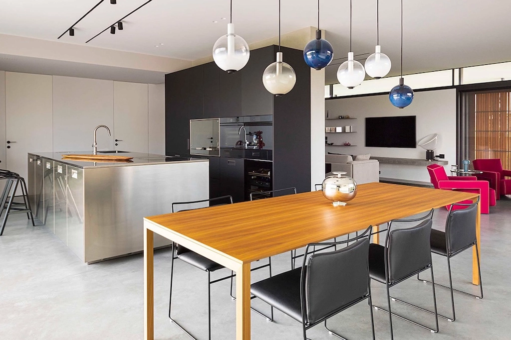 Casa CT — open plan kitchen with steel island, wooden dining table and pendant lights, interior design Vicenza