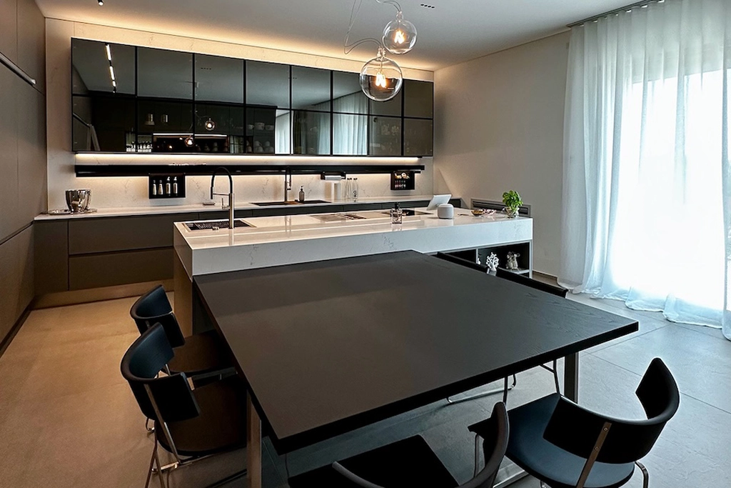 Casa CU — kitchen with smoked glass wall units, white marble island and integrated black table, interior design Vicenza