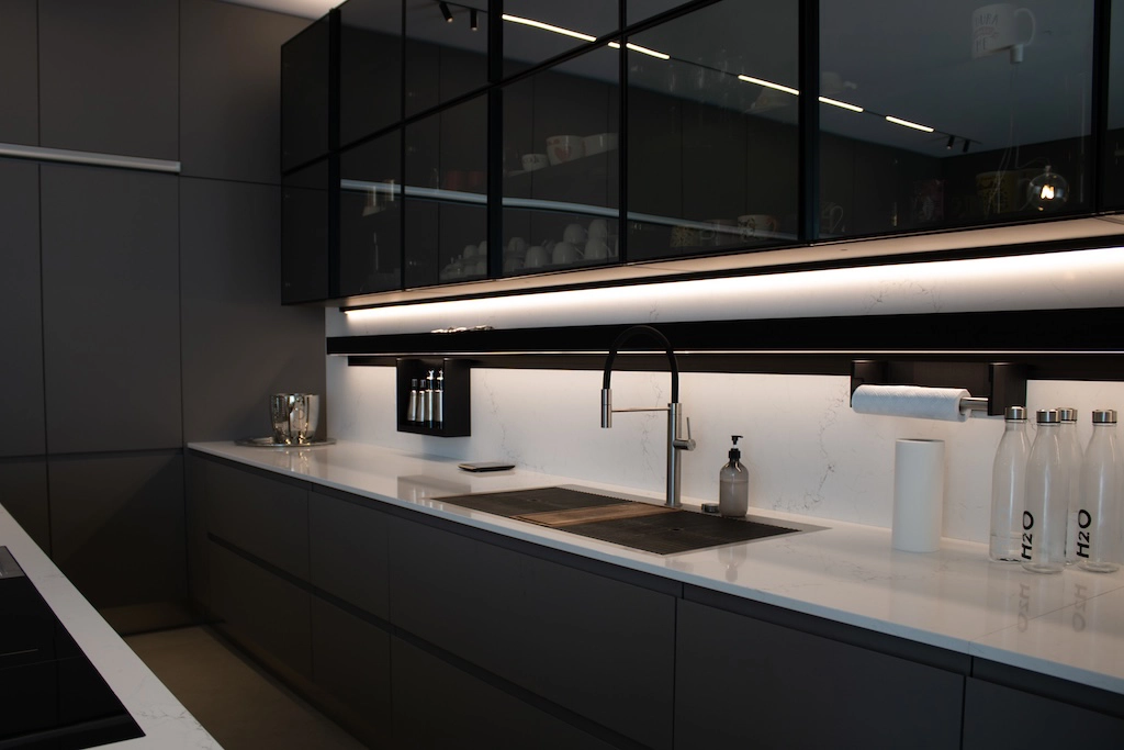 Casa CU — kitchen detail with smoked glass wall units, white marble worktop and LED under-cabinet lighting, interior design Vicenza