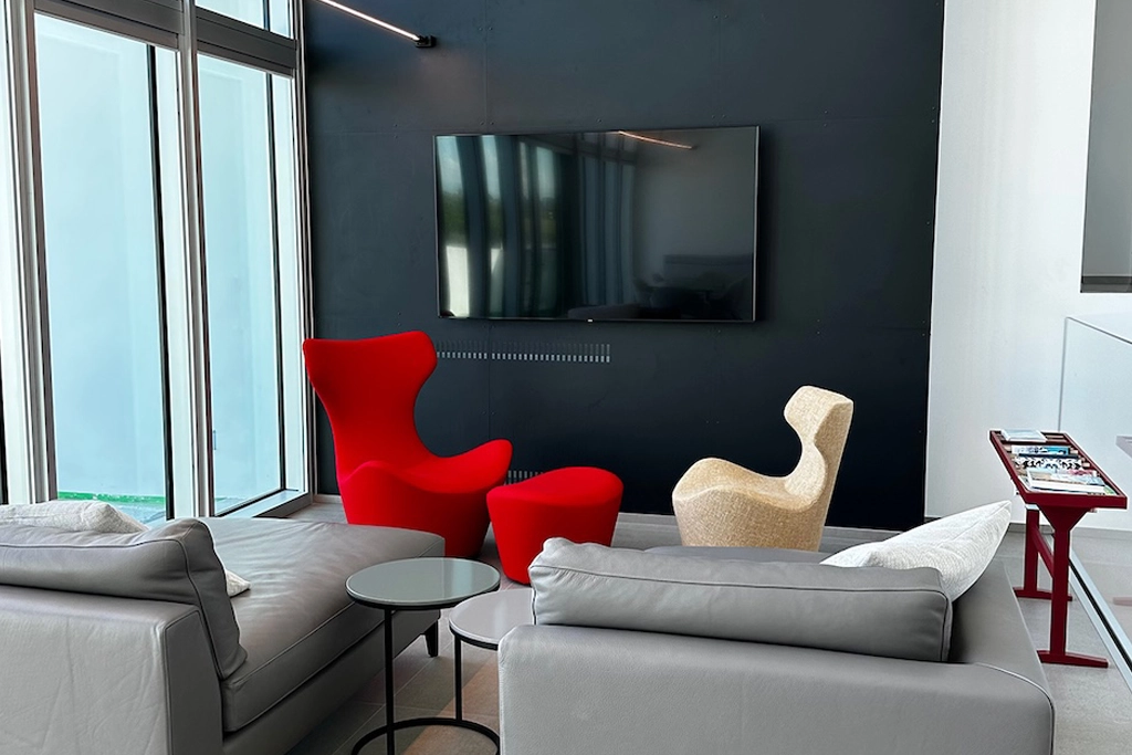 Casa UC — living room with grey sofas, red Moroso armchair and beige armchair against a black wall, interior design Vicenza