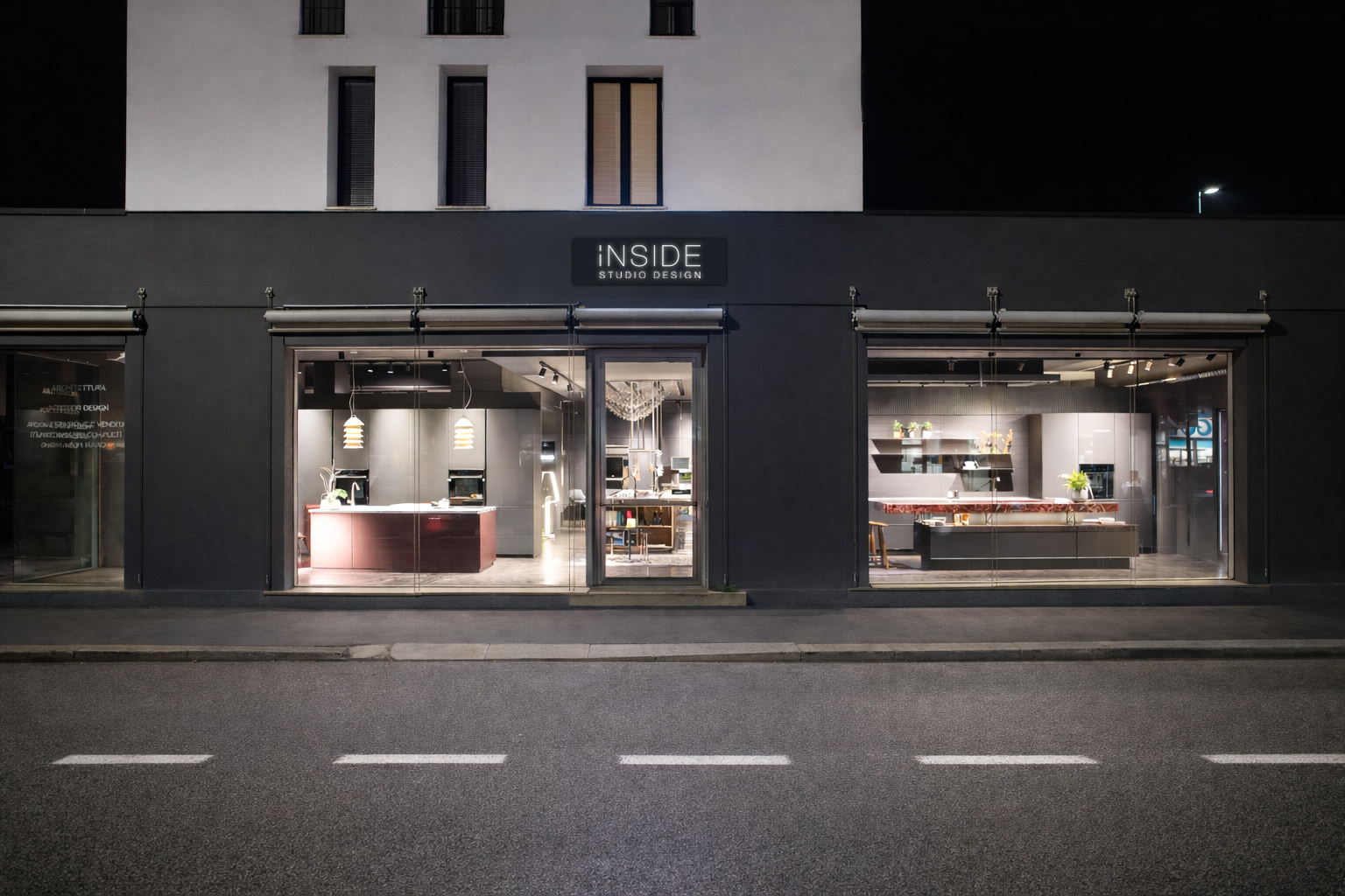 Exterior of the iNSIDE Studio Design showroom in Vicenza in the evening, with illuminated windows and displayed kitchens